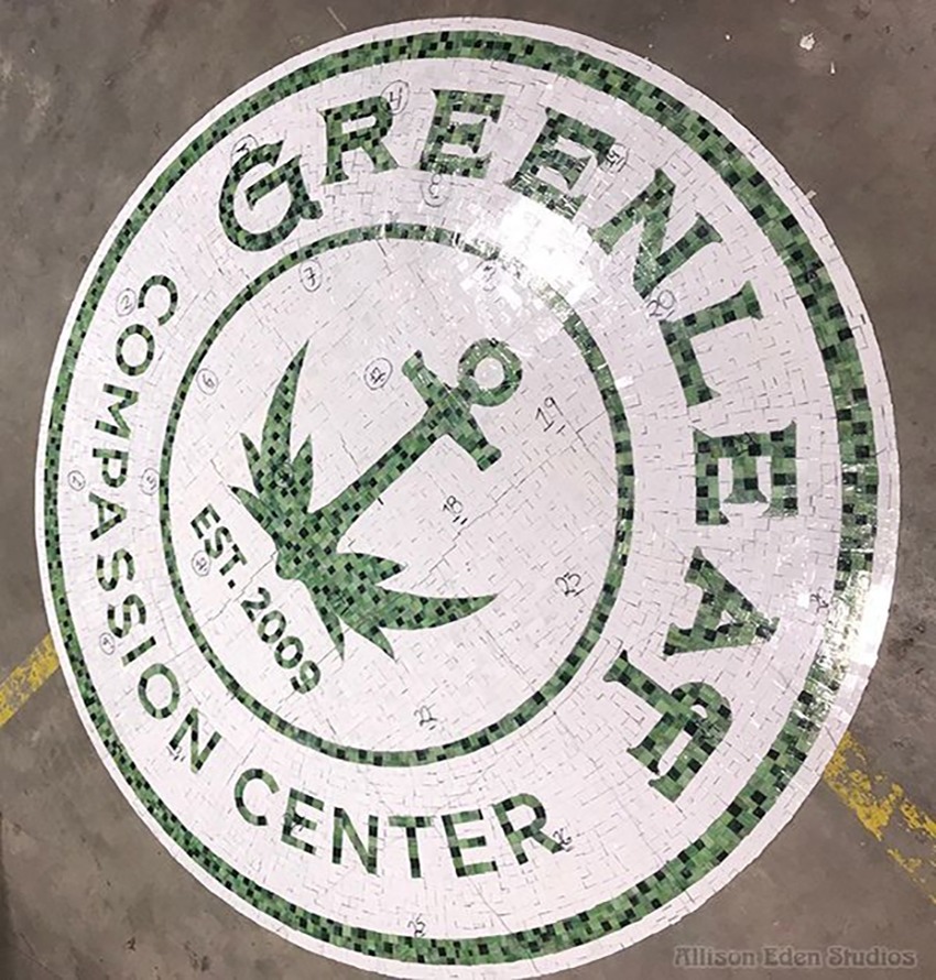 Greenleaf Compassion Center circular glass mosaic logo with green lettering and a leaf motif