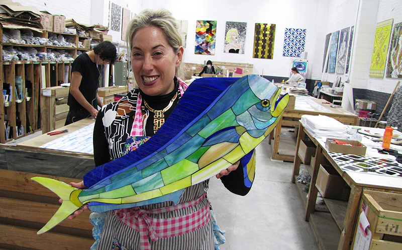 Allison Eden holding a handcrafted 30-inch mahi-mahi glass mosaic in her Brooklyn studio