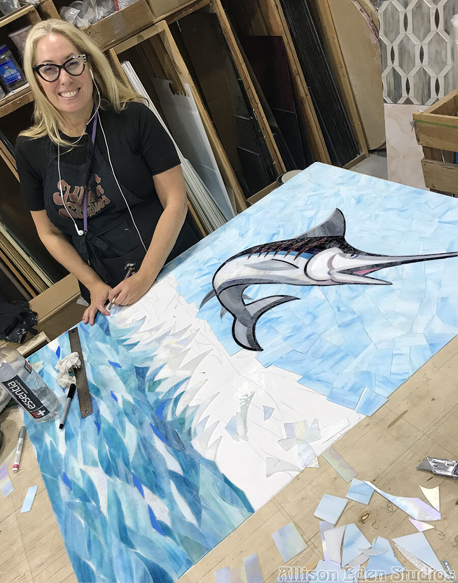Allison Eden making a custom swordfish glass mosaic mural from individually cut blue and iridescent glass
