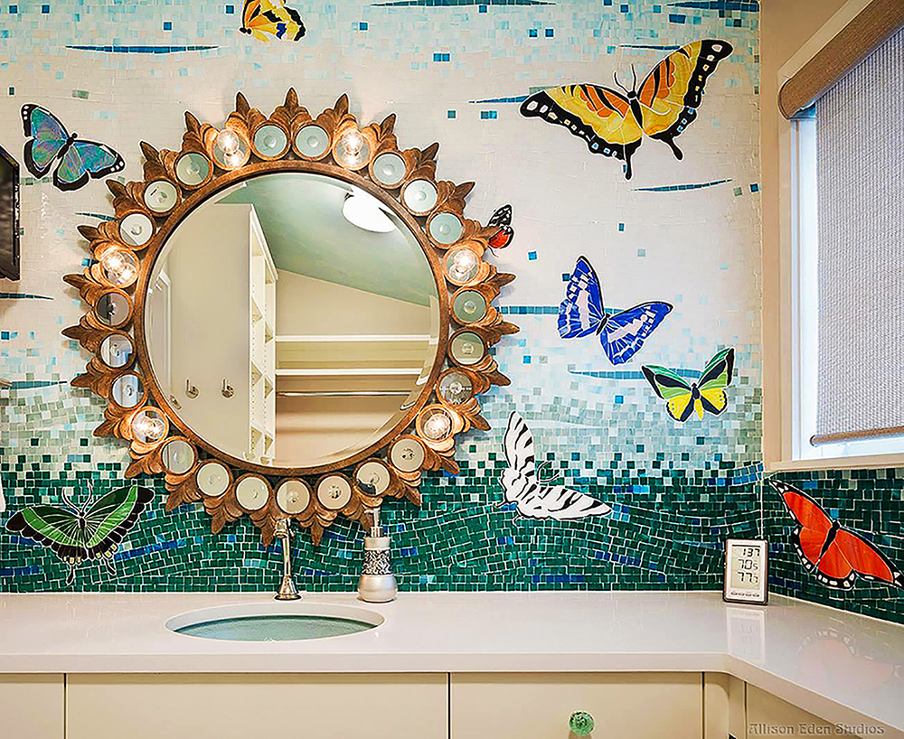 Custom stained glass butterfly mosaic bathroom mural by Allison Eden Studios with colorful butterflies flying across a blue and green ombré wall.
