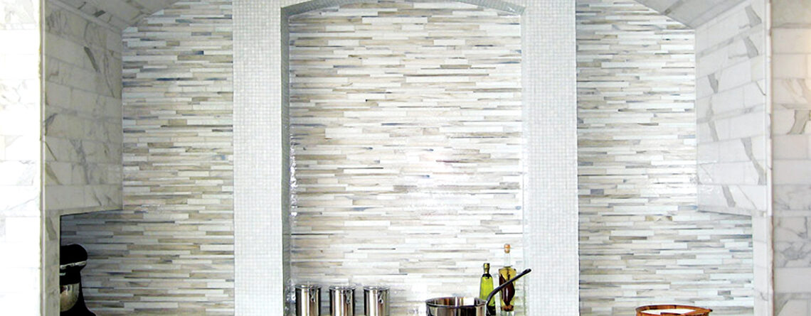 Luxury white and gray custom linear glass mosaic Barcode™ kitchen backsplash by Allison Eden Studios featuring handcrafted stained glass that complements Calacatta marble countertops, walls, and flooring in a contemporary designer kitchen.