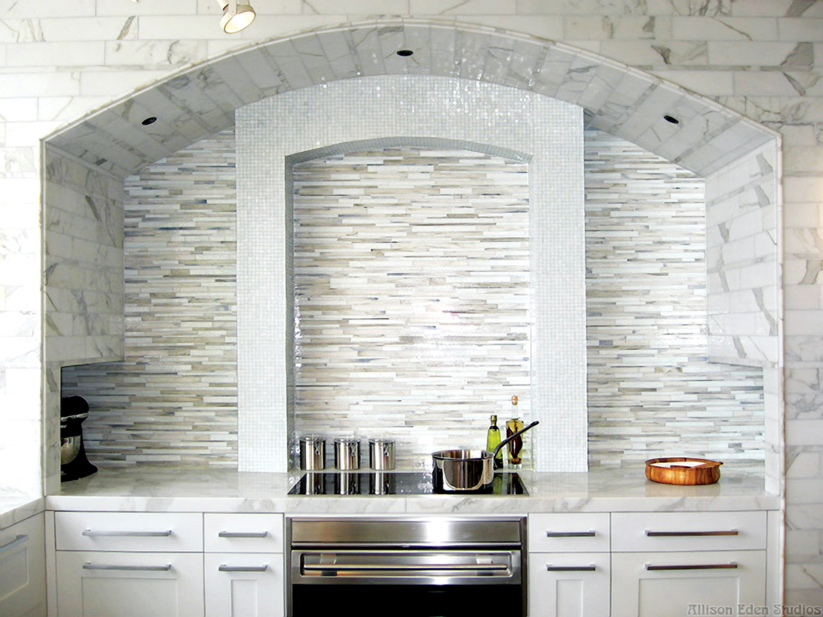 Luxury white and gray custom linear glass mosaic Barcode™ kitchen backsplash by Allison Eden Studios featuring handcrafted stained glass that complements Calacatta marble countertops, walls, and flooring in a contemporary designer kitchen.