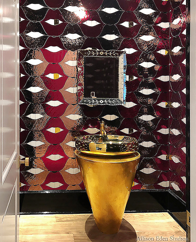 Gold pedestal sink surrounded by custom red SMILE Lips stained glass and mirror mosaic in a luxury powder room.