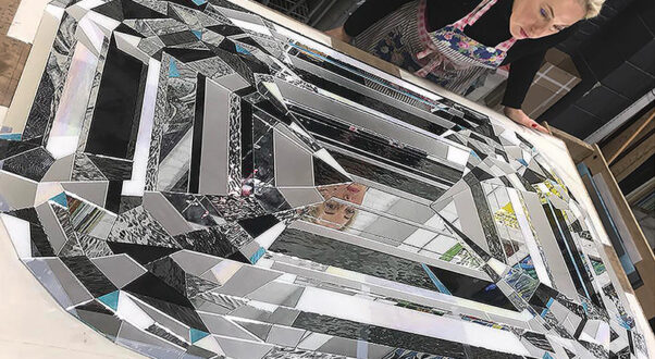 Artist Allison Eden creating a large custom glass diamond artwork from hand-cut stained glass and reflective mirror in her Brooklyn studio