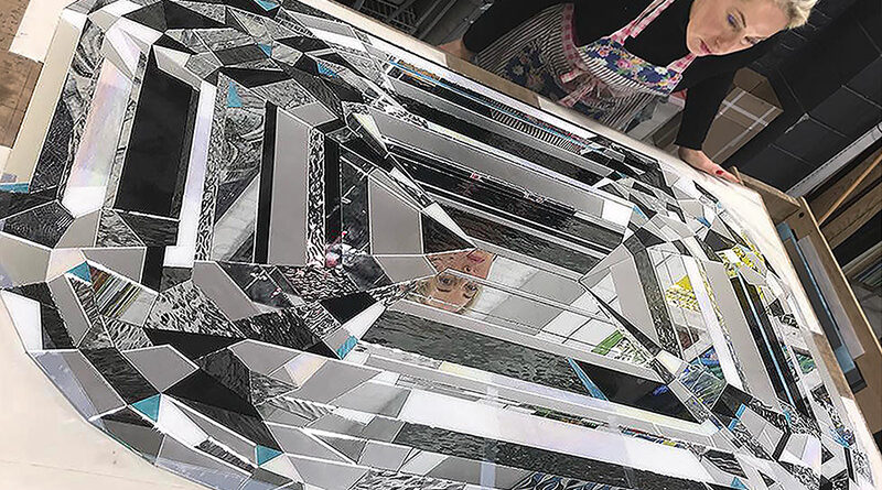 Artist Allison Eden creating a large custom glass diamond artwork from hand-cut stained glass and reflective mirror in her Brooklyn studio