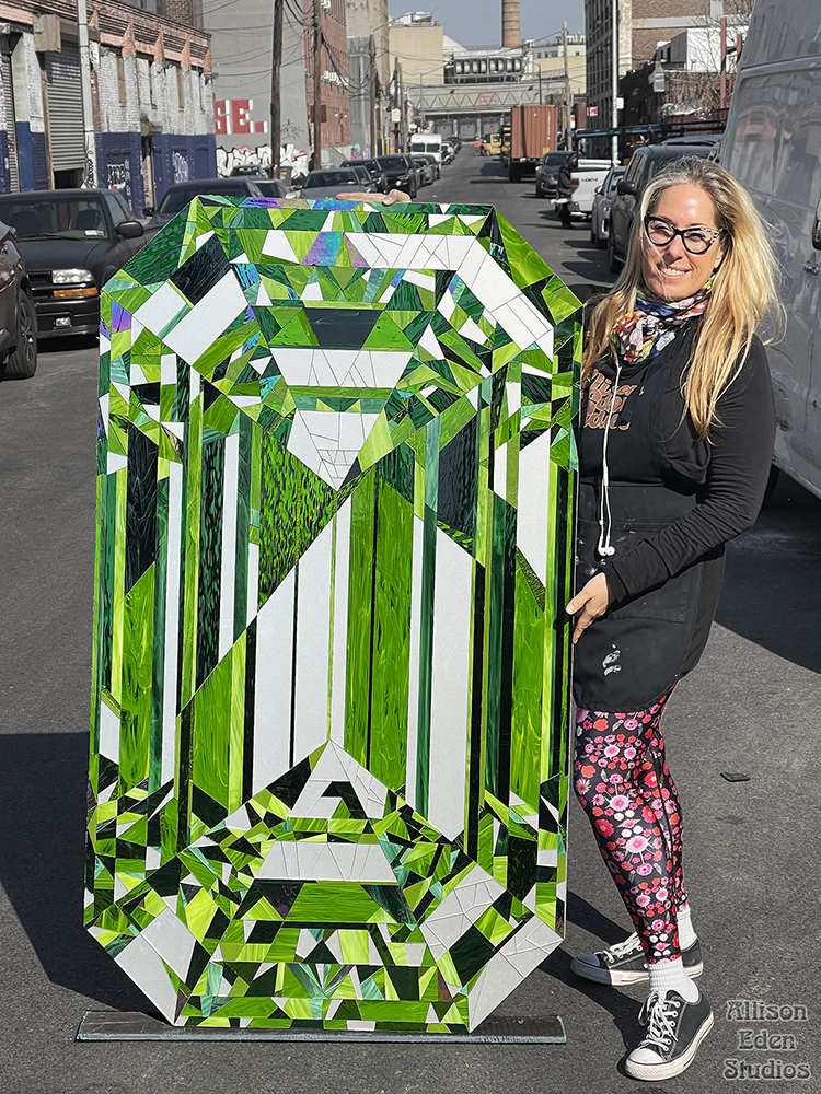 Artist Allison Eden with her monumental Emerald stained glass and mirror gemstone artwork handcrafted in Brooklyn.