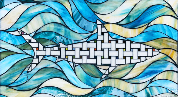 Handcrafted stained glass shark mosaic artwork by Allison Eden Studios featuring a geometric shark swimming through layered blue, turquoise and ivory ocean waves.