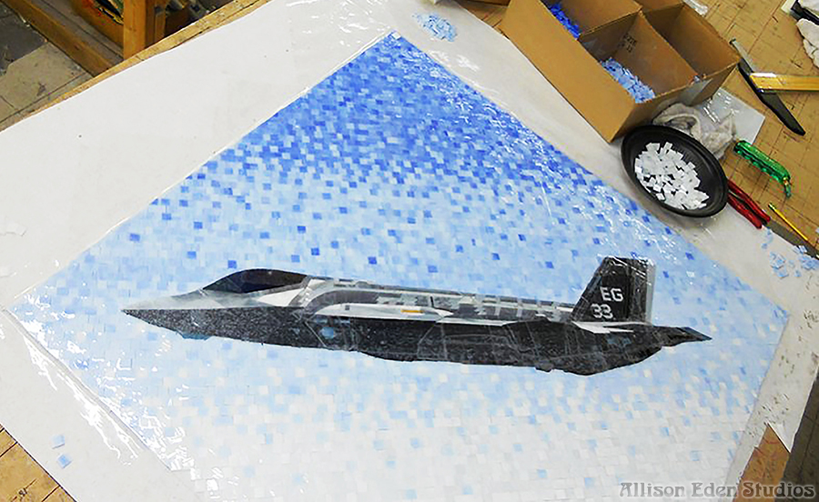 Handcrafted Lockheed Martin F-35 Lightning II stained glass mosaic in progress at Allison Eden Studios featuring realistic aircraft artwork against a blue mosaic sky.