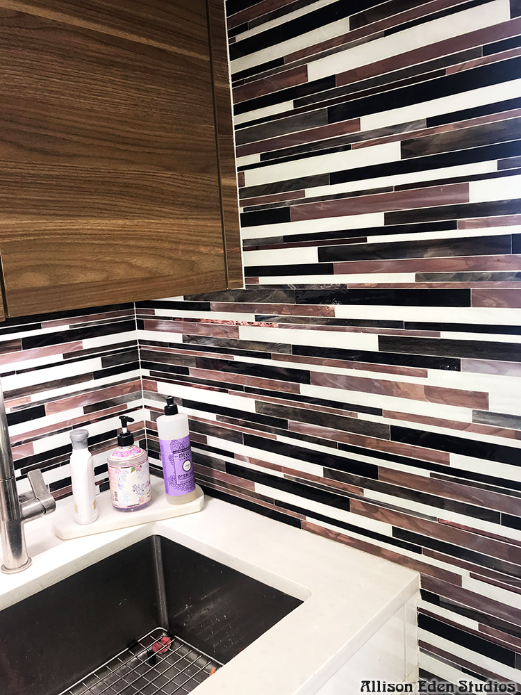 Modern custom Barcode glass mosaic kitchen backsplash by Allison Eden Studios featuring handcrafted linear stained glass tiles in plum, ivory, black, and gray installed in a contemporary luxury kitchen corner.
