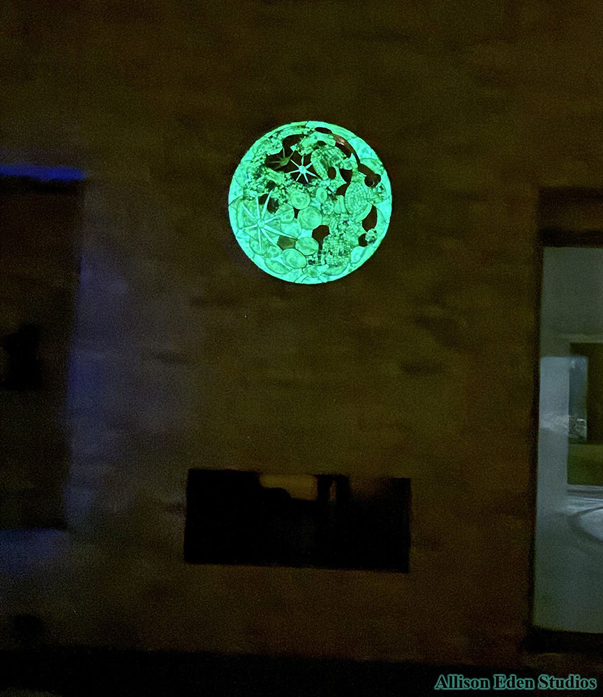 Allison Eden’s glow-in-the-dark glass mosaic moon artwork illuminated at night at Villa Luna in the Hamptons.