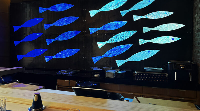 Handcrafted blue and turquoise stained glass mosaic fish illuminated from behind at Bondi Sushi in New York City.mosaic nyc small