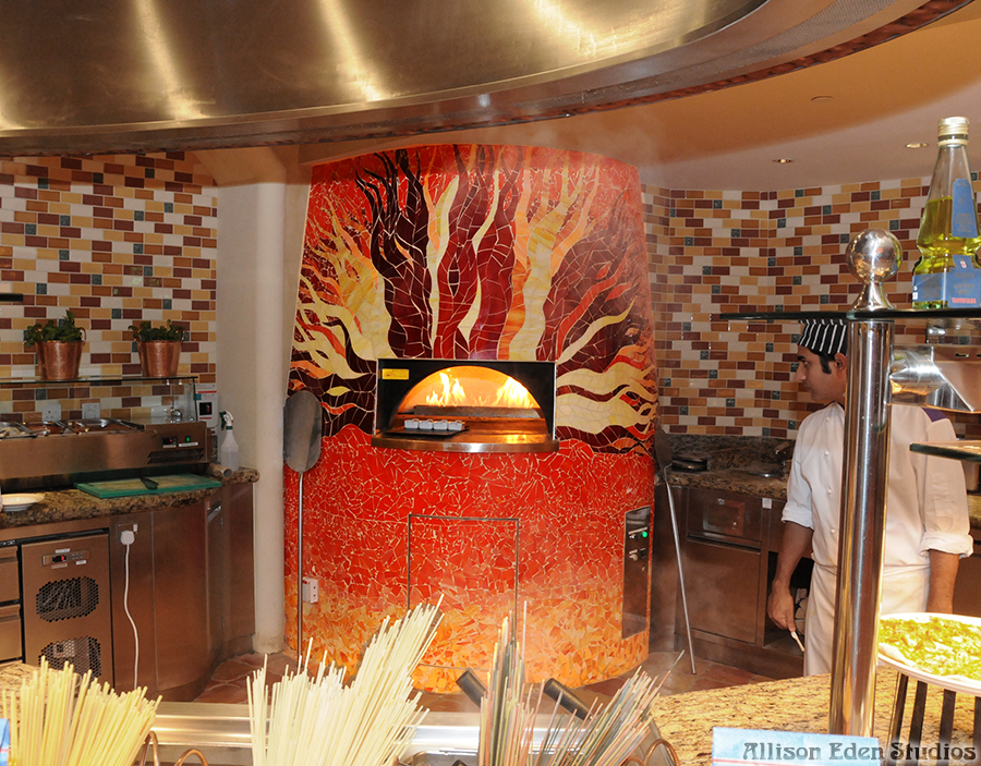 Custom red and orange stained glass mosaic pizza oven surround by Allison Eden Studios for a restaurant at Atlantis Dubai.
