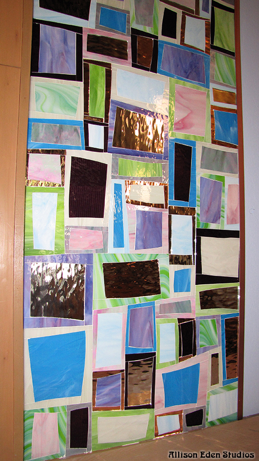 Close-up of Allison Eden Studios’ Tiki Block stained glass mosaic in soft green, blue, pink, cream and reflective glass tones.