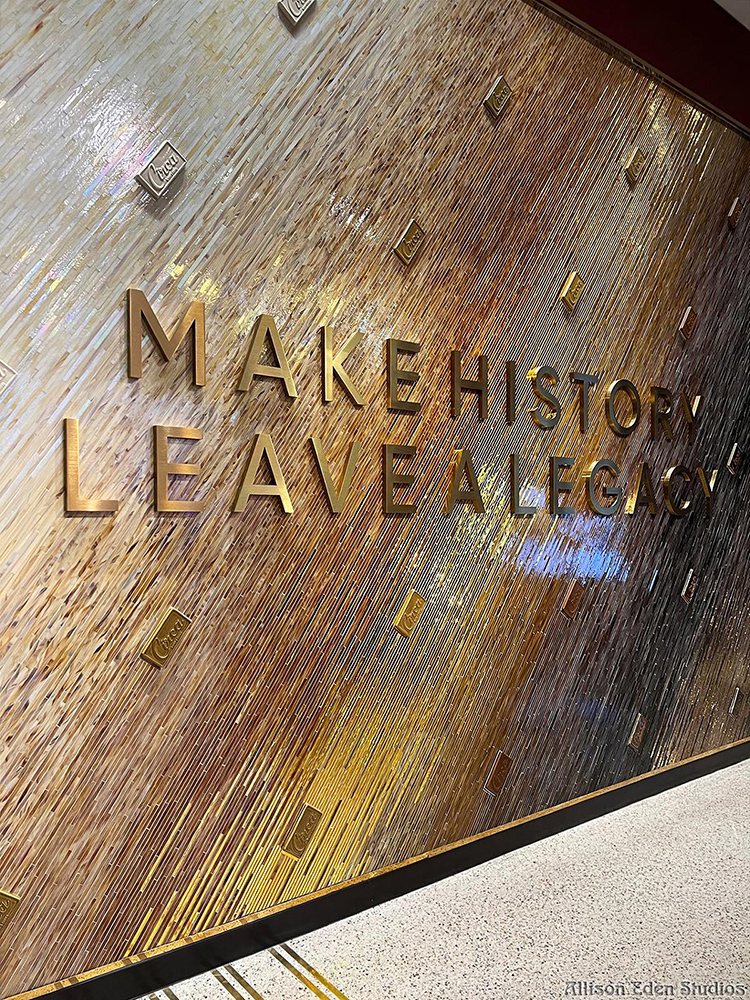 Angled view of the Circa Casino glass mosaic wall by Allison Eden, showing gold lettering, integrated Circa logo elements, and shimmering ivory-to-bronze glass gradation.
