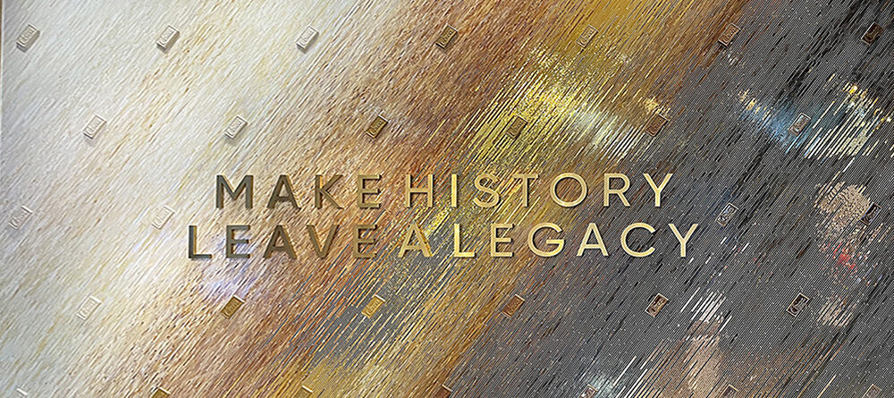 Close-up of Allison Eden's stained glass mosaic at Circa Las Vegas, featuring gold Make History Leave a Legacy lettering and a diagonal gradation of ivory, amber, and charcoal glass.