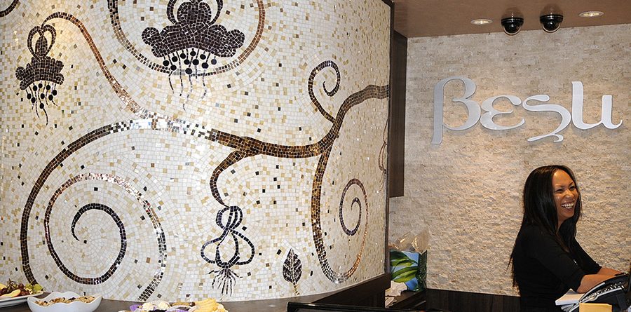 Custom floral glass mosaic mural by Allison Eden behind the curved reception desk at BeSu Salon & Day Spa in New York City.