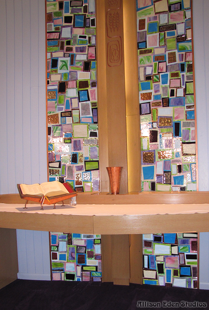 Handcrafted stained glass mosaic behind the altar and cross in a Pennsylvania church sanctuary.