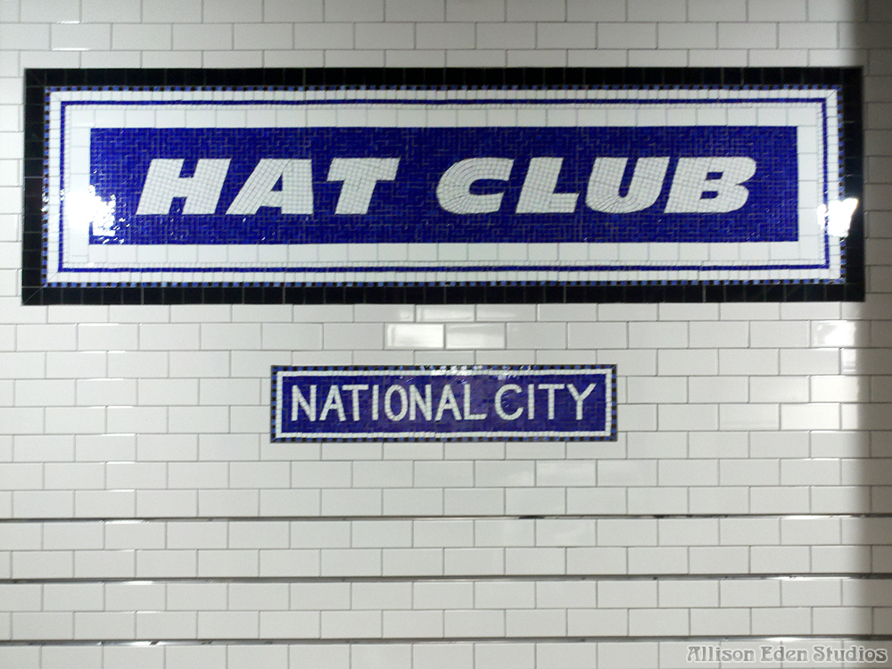 Hat Club retail interior featuring a large cobalt blue and white glass mosaic logo and matching National City sign on a white subway tile wall beside merchandise displays.