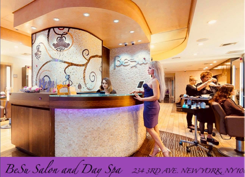 Interior of BeSu Salon & Day Spa NYC featuring a curved reception desk, custom glass mosaic floral wall, and contemporary salon styling stations.