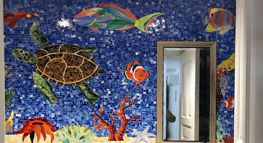 Close-up of a handcrafted stained glass sea turtle and tropical fish within a custom aquatic mosaic mural by Allison Eden Studios.